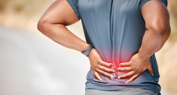 Man experiencing lower back pain, holding his lower back with a pained expression, emphasizing the impact of back pain.