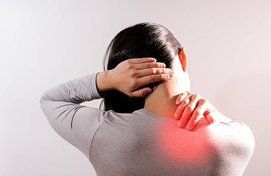 Woman experiencing neck and shoulder pain, illustrating symptoms treated by chiropractic care for neck pain and discomfort.