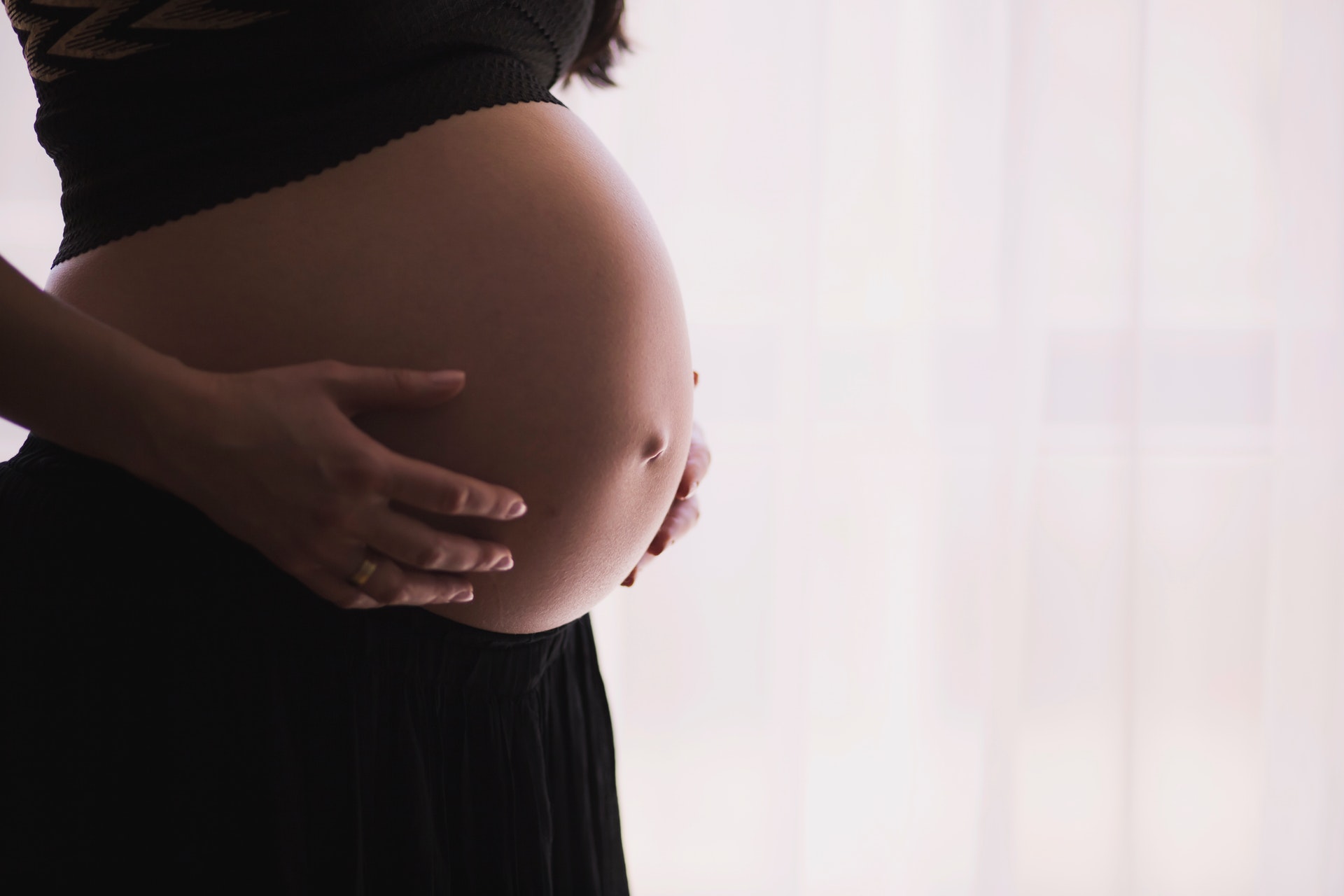 Pregnant woman gently cradling her baby bump, highlighting prenatal care benefits related to chiropractic services at Active Life Chiropractic.